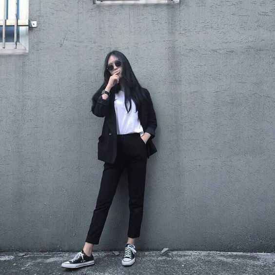 Office woman wearing a monochrome outfit with a blazer, sneakers and sunglasses