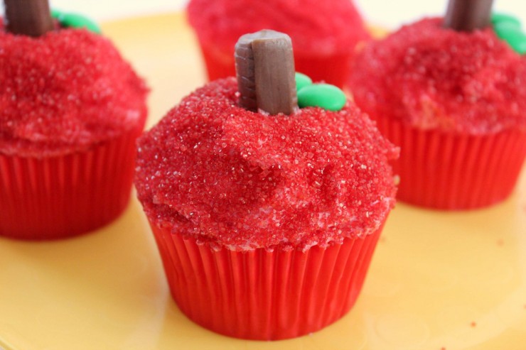 cupcakes decorated to look like apples with red sugar, chocolate biscuits and green chocolate