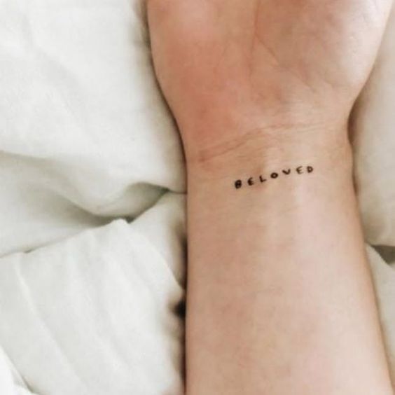 Girl with a small and minimalist wrist tattoo of a quote in typewriter style font