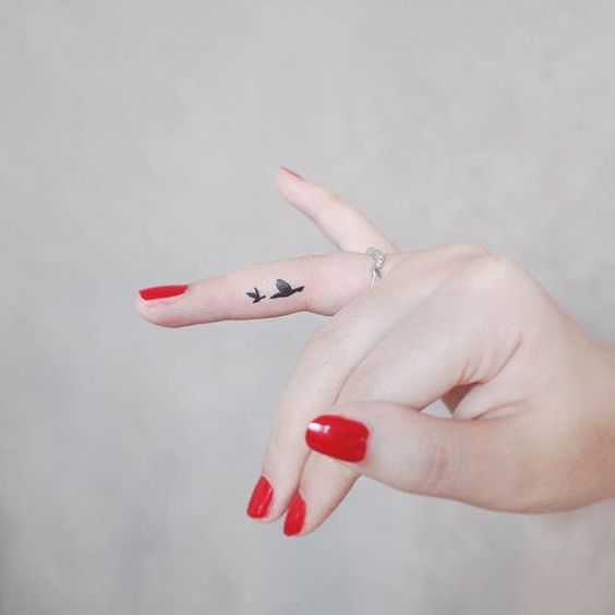 Girl with a small and minimalist finger tattoo of birds