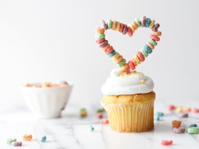 cupcake with white frosting and fruit loops arranged in the shape of a heart