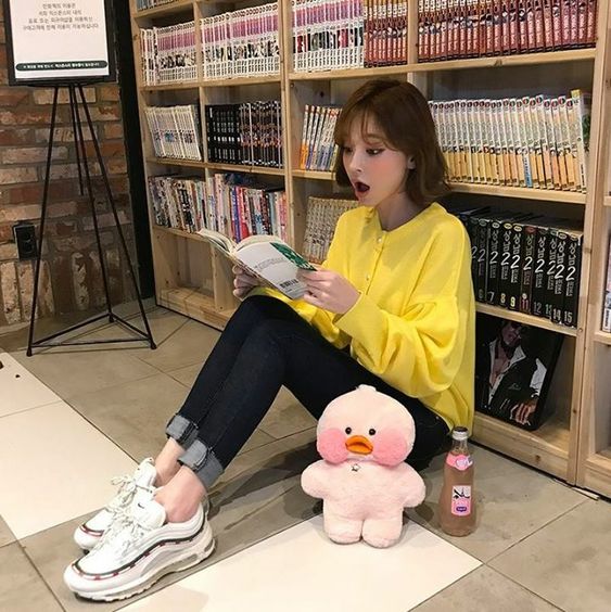 korean girl wearing a yellow top while reading manga