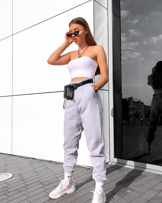 girl wearing a crop top, pants, sneakers, sunglasses and a fanny pack