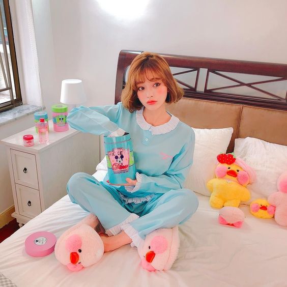 korean girl sitting on her bed while in blue pajamas