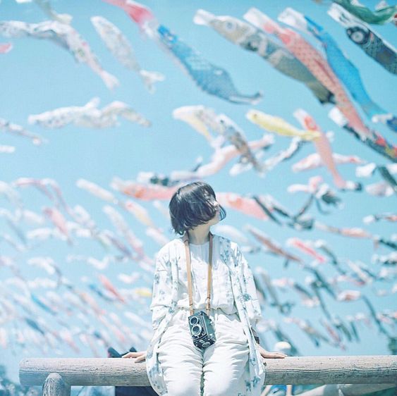 girl with a camera looking at fish lanterns in the background