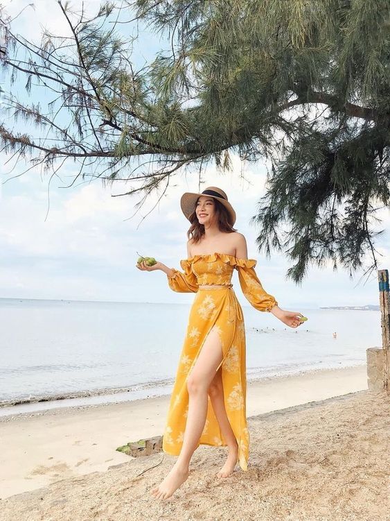 asian woman wearing a yellow dress with slits and a hat