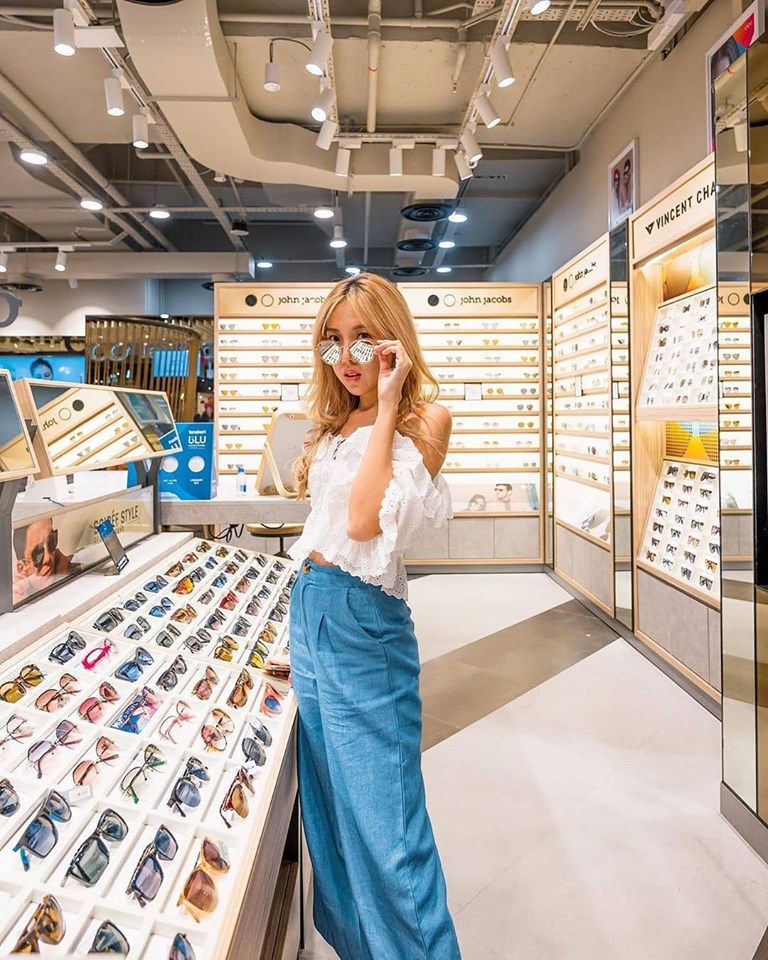 asian girl wearing a white top and jeans while shopping for glasses and sunglasses in a Lens Kart store