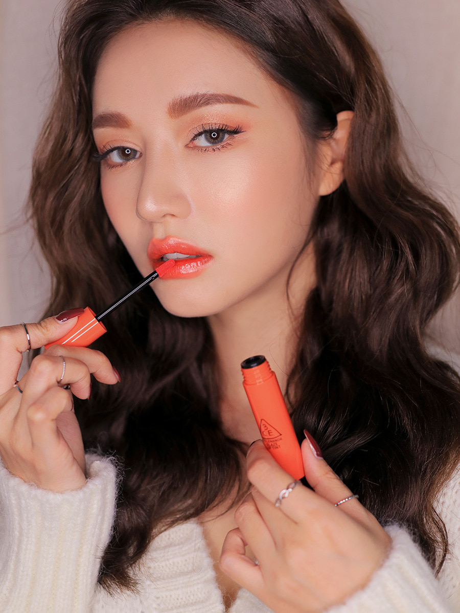 Glaze Lip Tint in classic coral shade applied by model