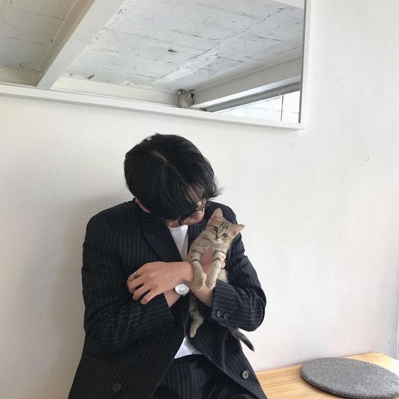 asian guy wearing black and holding a brown cat