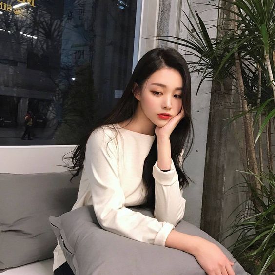 asian girl wearing a white top and holding a cushion