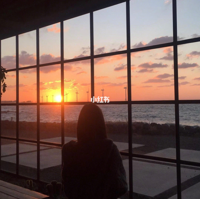 Girl looking a sunrise through the window