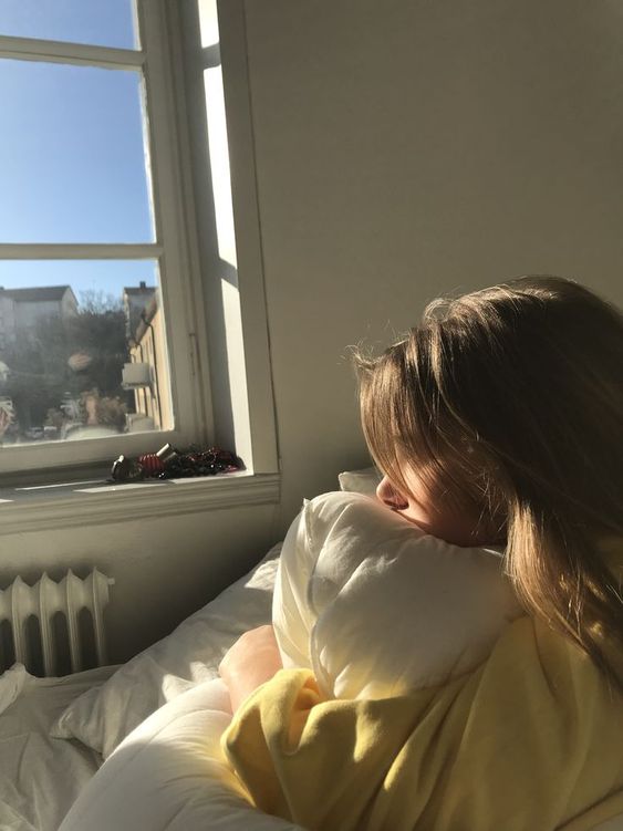 Girl sitting on the bed looking out the window