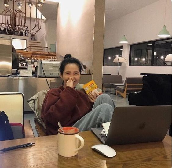 asian girl eating while using her laptop