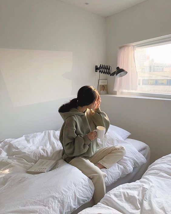 Girl sitting on the bed with a cup of coffee