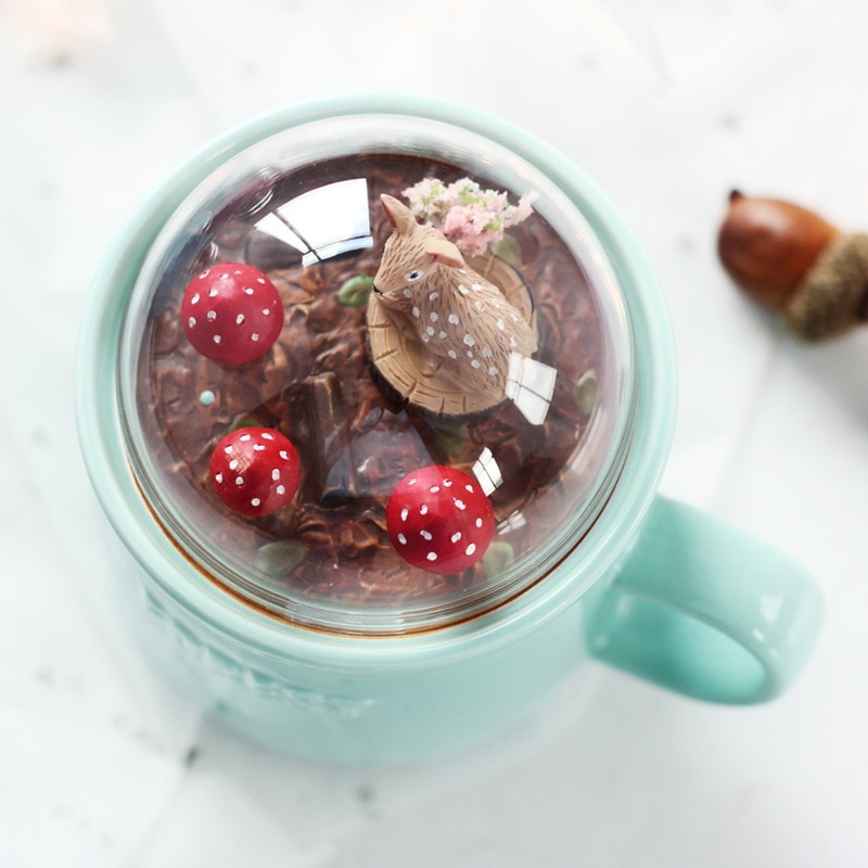ceramic mug comes with a glass dome lid that has woodland creatures in a forest