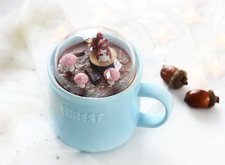 ceramic mug comes with a glass dome lid that has woodland creatures in a forest