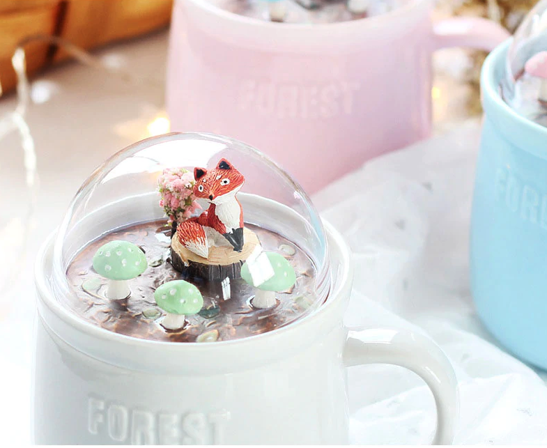 ceramic mug comes with a glass dome lid that has woodland creatures in a forest