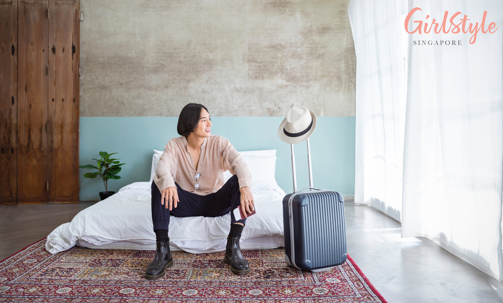asian man in a hotel room with carpet and blue and grey walls