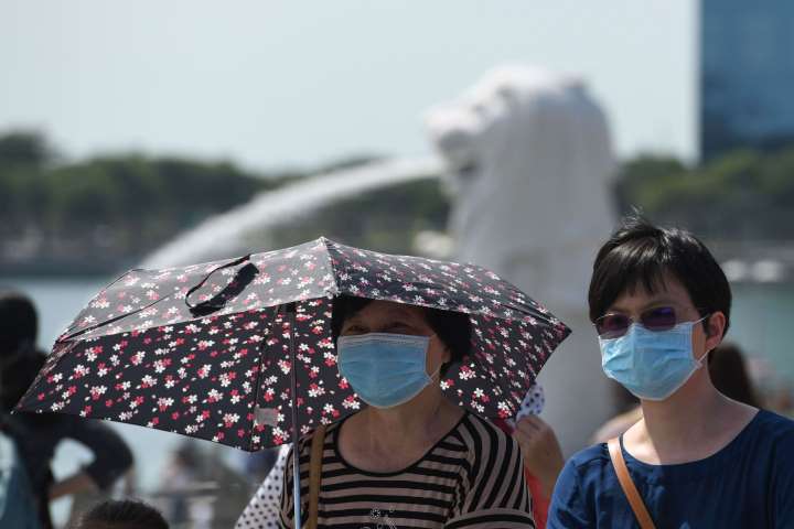 Two ladies wearing mask near Merlion