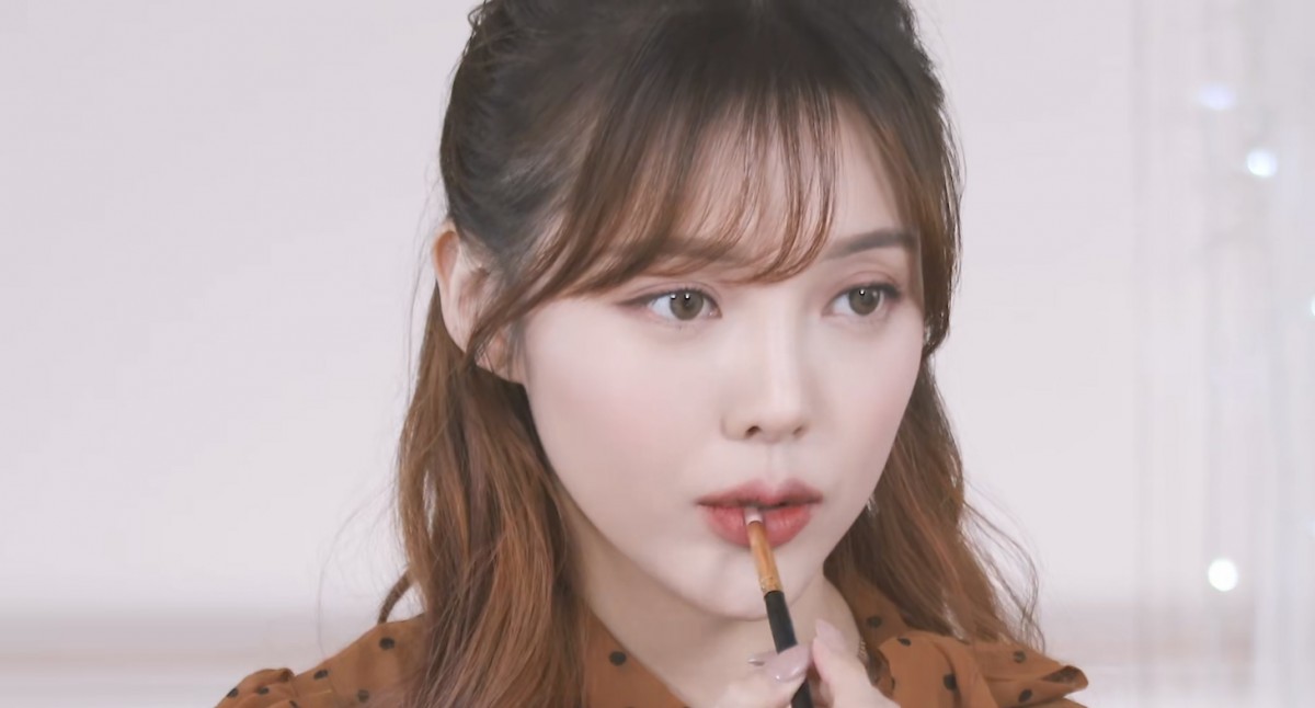 Pony applying eyeshadow on her lower lip