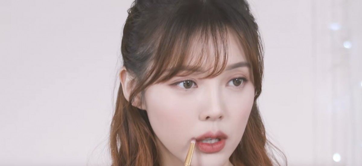 Pony applying eyeshadow on the corner of her lips