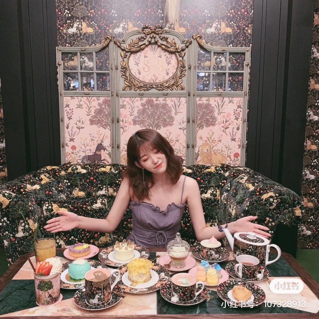 Girl posing in Sretsis Parlour with desserts and drinks on the table