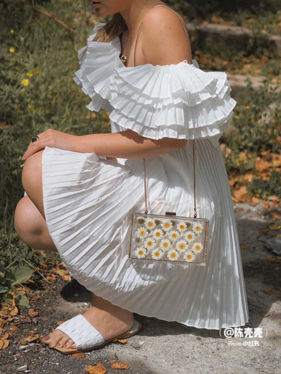 Girl squatting on the floor carrying the ZARA transparent daisy bag