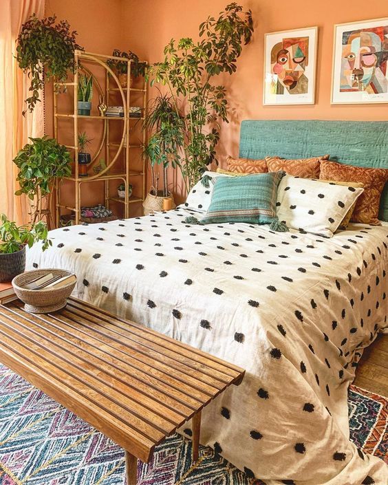 warm bedroom with patterned bedding, plants and rattan furniture