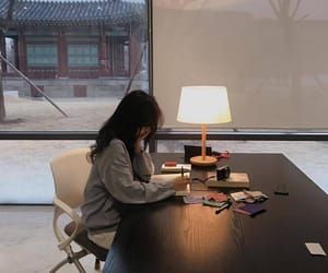 asian woman writing on a desk with a lamp