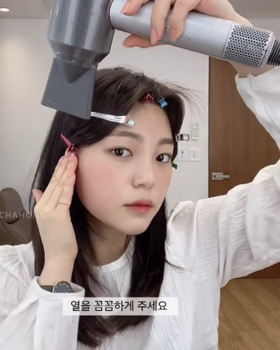 asian girl styling middle hair parting with clips and a hairdryer