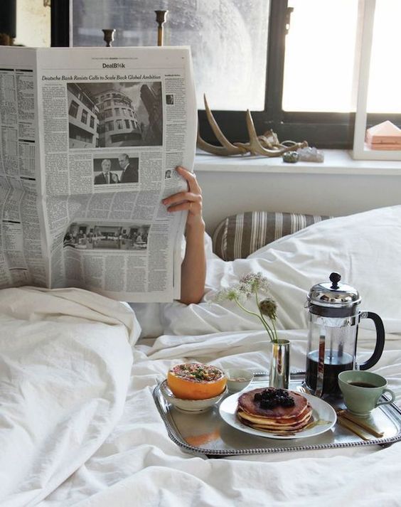 Breakfast in bed with pancakes and reading the newspaper