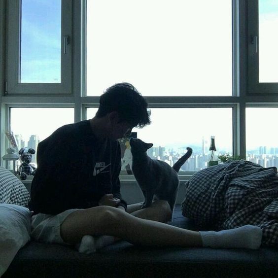 korean ulzaang boy sitting in bed and kissing his dog