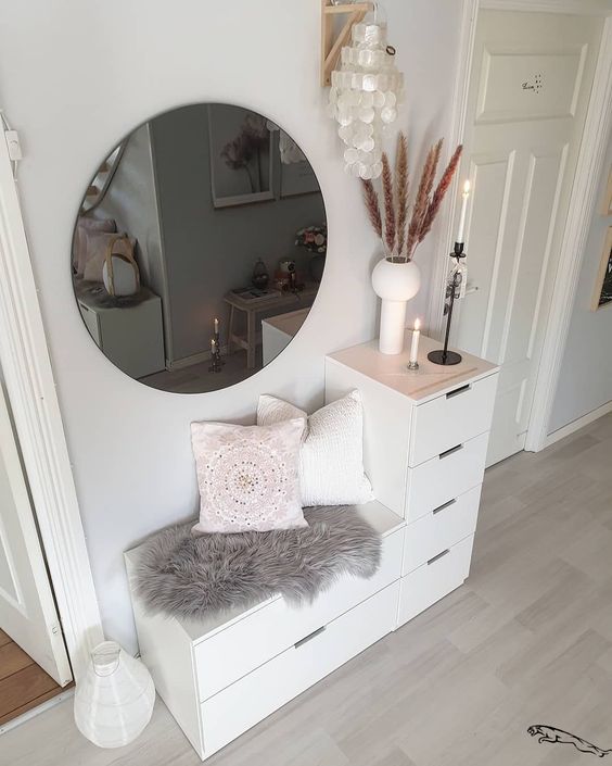 small entryway with shoe storage that is also seats with a round mirror