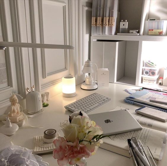 minimalist work desk with MacBook laptop, files and flowers