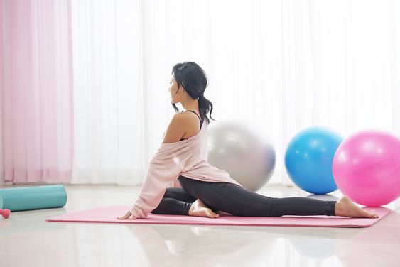 asian woman doing yoga poses on a pink yoga mat