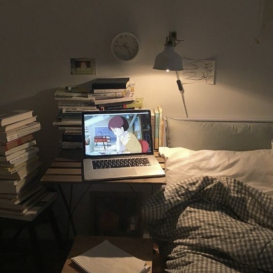 Laptop on a table with stacks of books