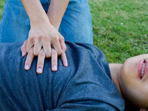 person giving cpr chest compressions to a man