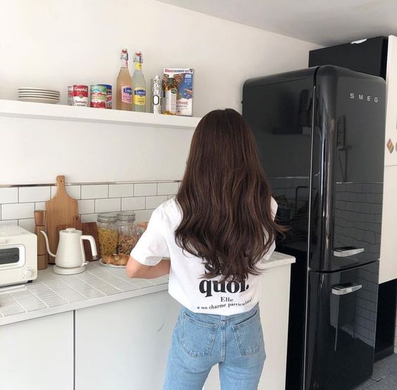 Asian girl with long hair standing in the kitchen with smeg refidgerator