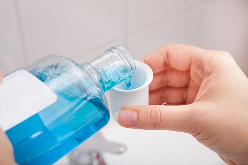 Close-up Of Person's Hand Pouring Liquid In Container
