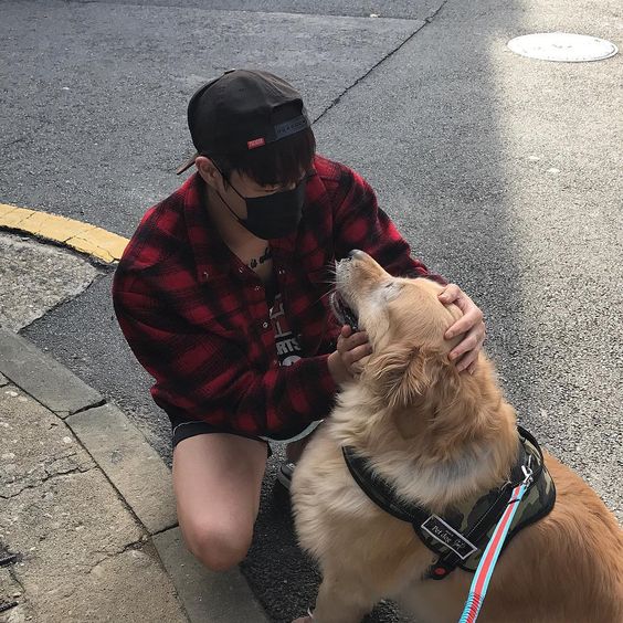 asian guy wearing a mask in plaid shirt petting his leashed dog