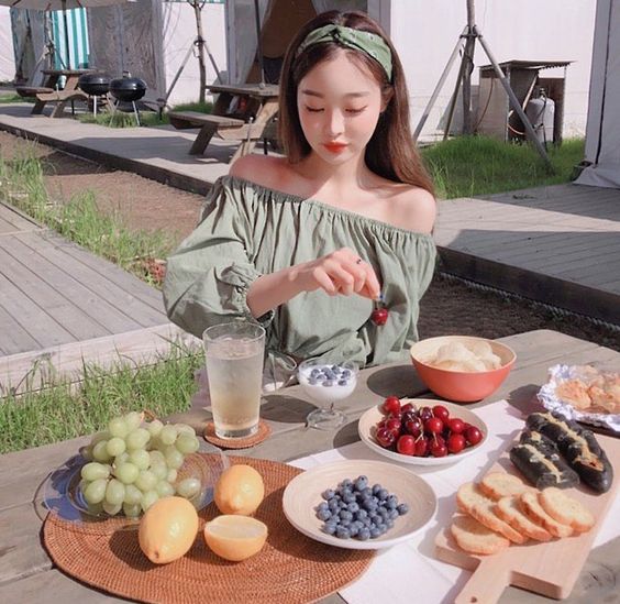 asian girl wearing a green off shoulder top eating fruits