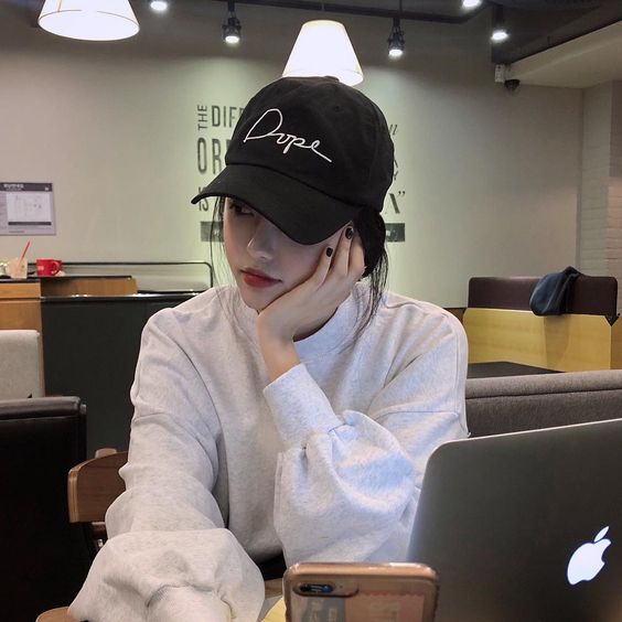 asian girl in front op laptop wearing a cap