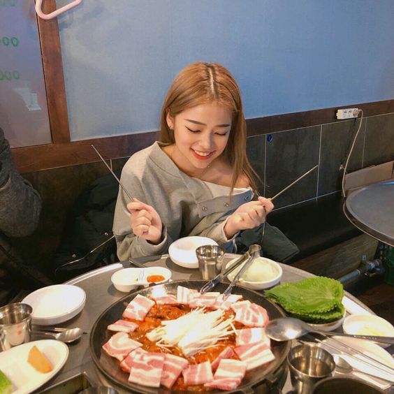 asian girl eating korean bbq meat and holding chopsticks
