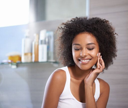 woman applying moisturiser in bathroom