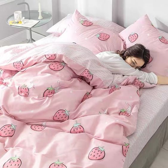 Girl laying in bed with strawberry bed sheets