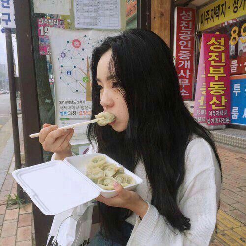 asian girl eating takeaway mandu street food in Korea