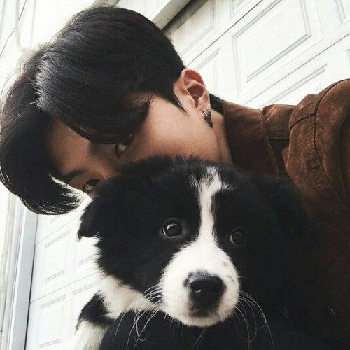 asian guy holding a black and white dog