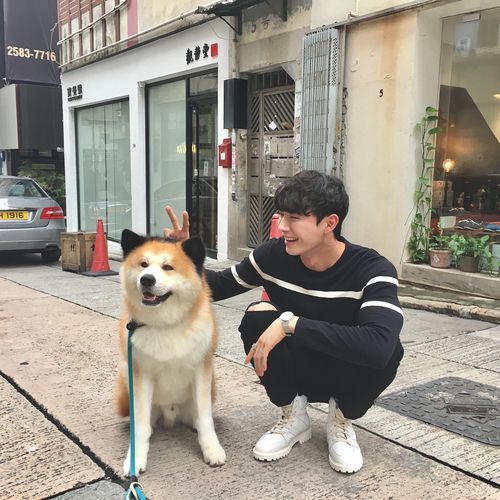 asian guy squatting down next to a Shiba Inu
