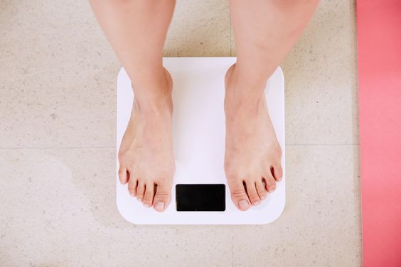 woman standing on a white weighing scale machine