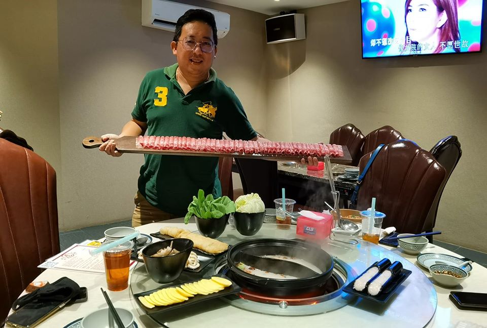 man holding raw meat at hotpot restaurant